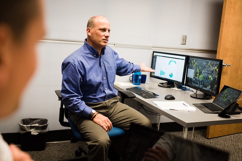 Man pointing at computer screen with charts and graphs on it