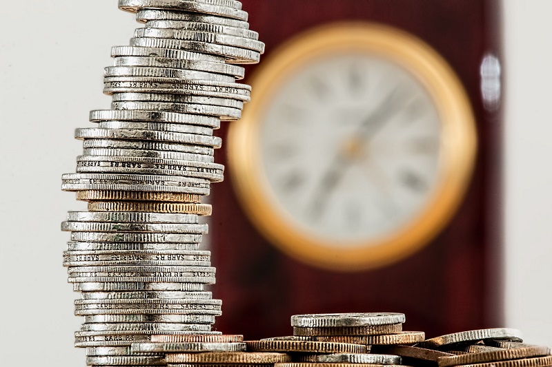 Coins in foreground with clock in background