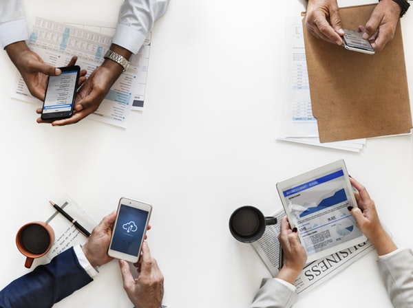 Three people using smartphones and one person using a tablet