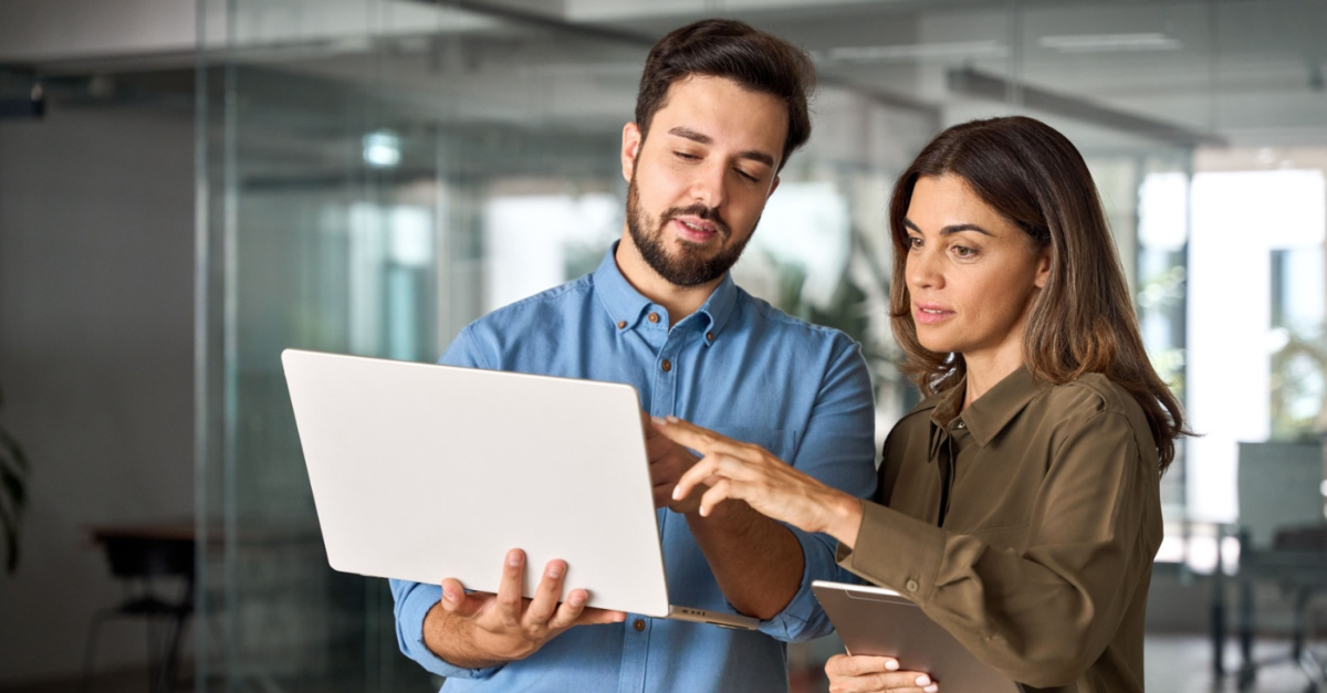 Two business professionals reviewing data on a laptop in a modern office, discussing insights powered by advanced analytics for better decision-making.
