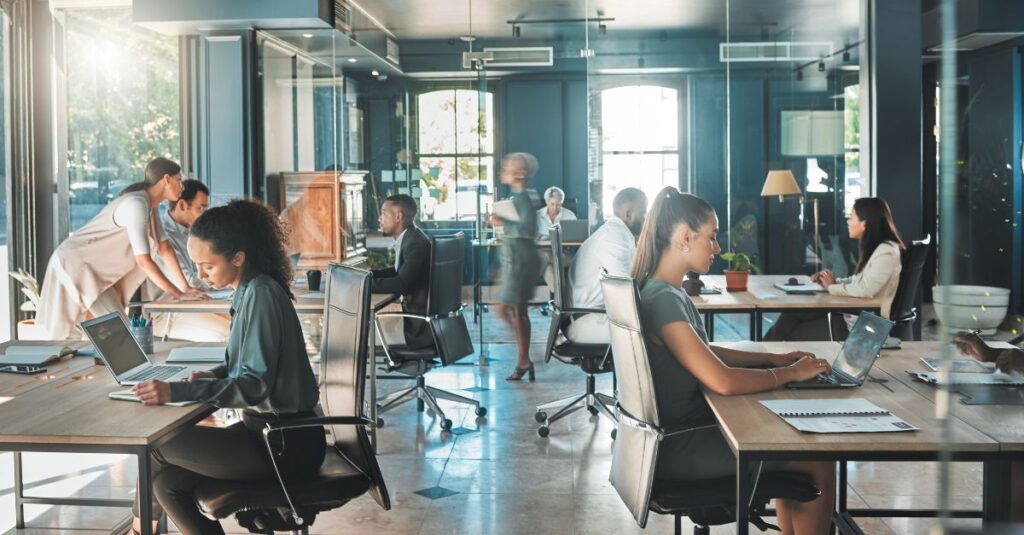 Employees collaborating and working on laptops in a bright, open-concept office, showcasing a Modern Workplace with contemporary design and digital productivity tools.
