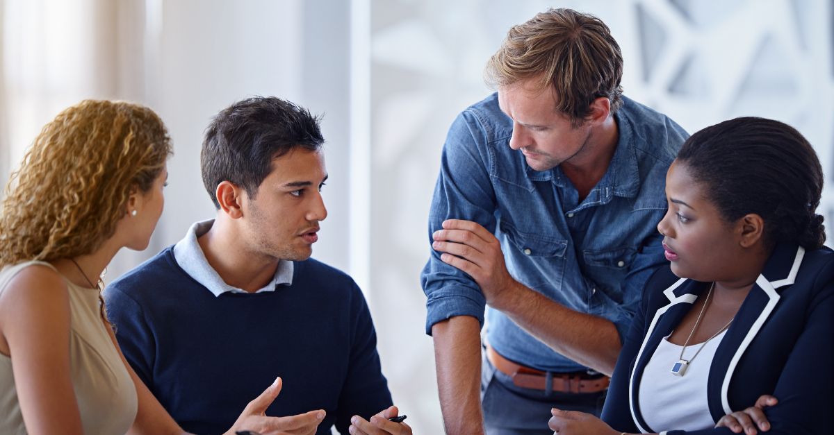 Four coworkers in an office planning meeting discussing GP to Business Central migration strategy