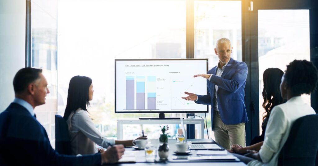 Business leaders reviewing performance dashboards during a strategy meeting, demonstrating Business Central Microsoft 365 integration through collaborative reporting and real-time insights on a shared screen.